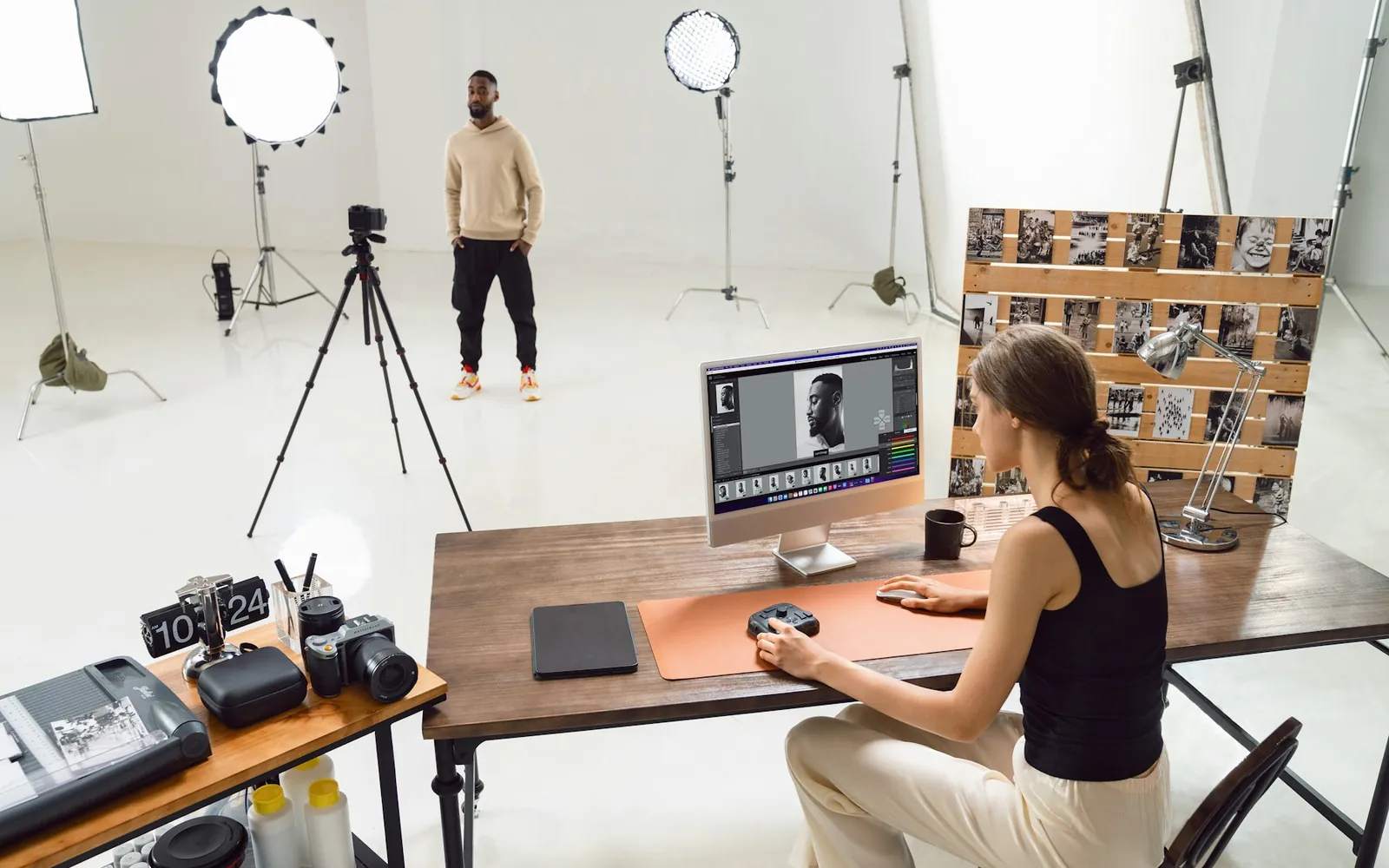 A photographer retouching studio portraits on a computer beside the shoot.