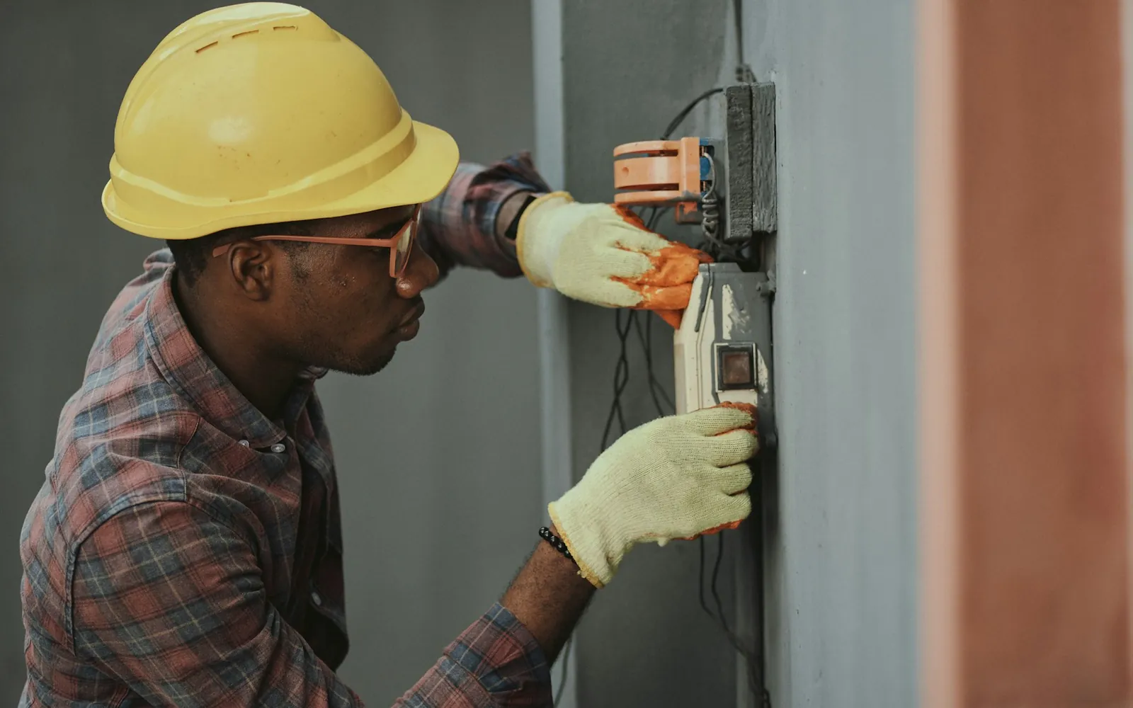 A maintenance technician in a hard hat working on an electrical installation.