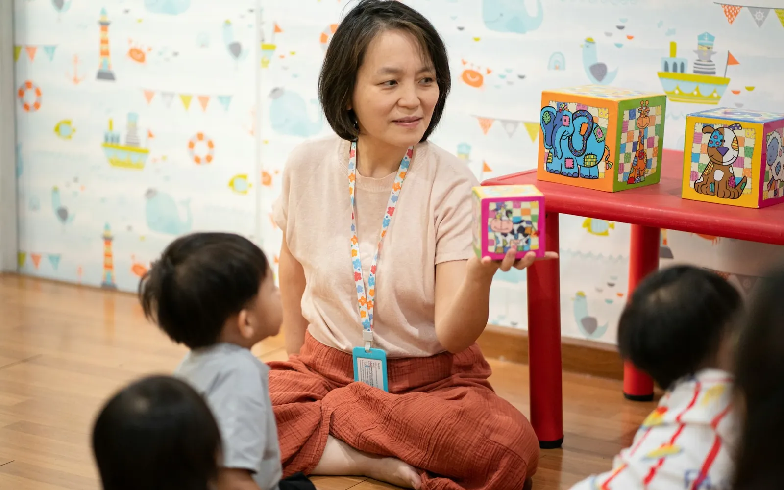 A teacher using colourful blocks to teach a group of young children.