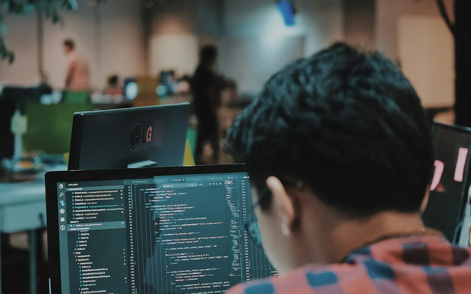 A developer writing code at a multi-screen workstation.