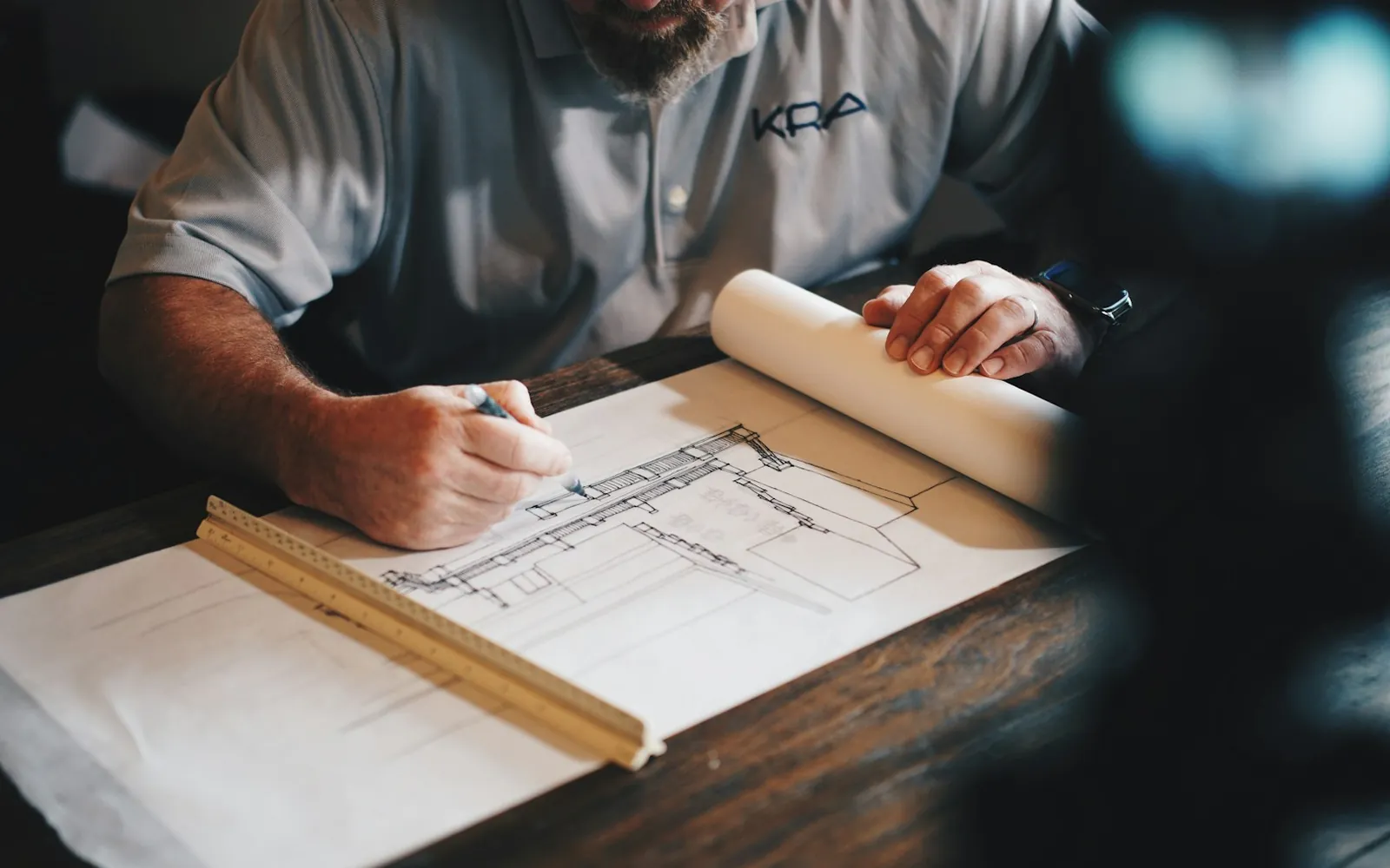 An architect drafting a technical drawing with a scale rule.