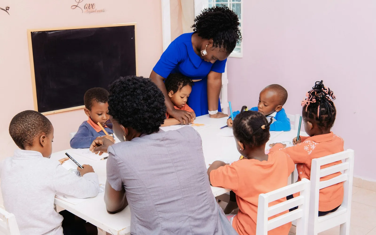 A teacher guiding young children through a drawing activity.